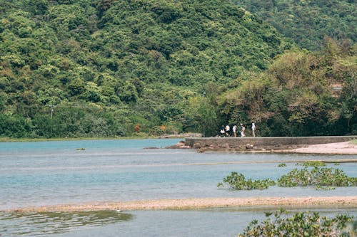 People are walking along the shore of a lake