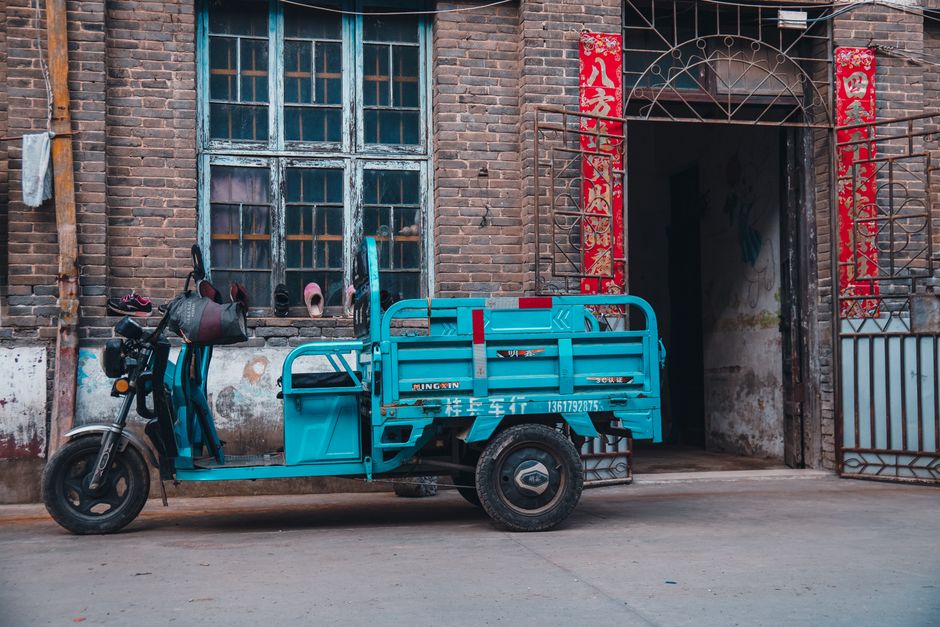 A blue scooter is parked outside a traditional brick building in Jiujiang, China.