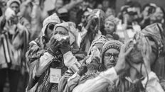 Men in traditional attire play conch shells in a vibrant cultural festival.