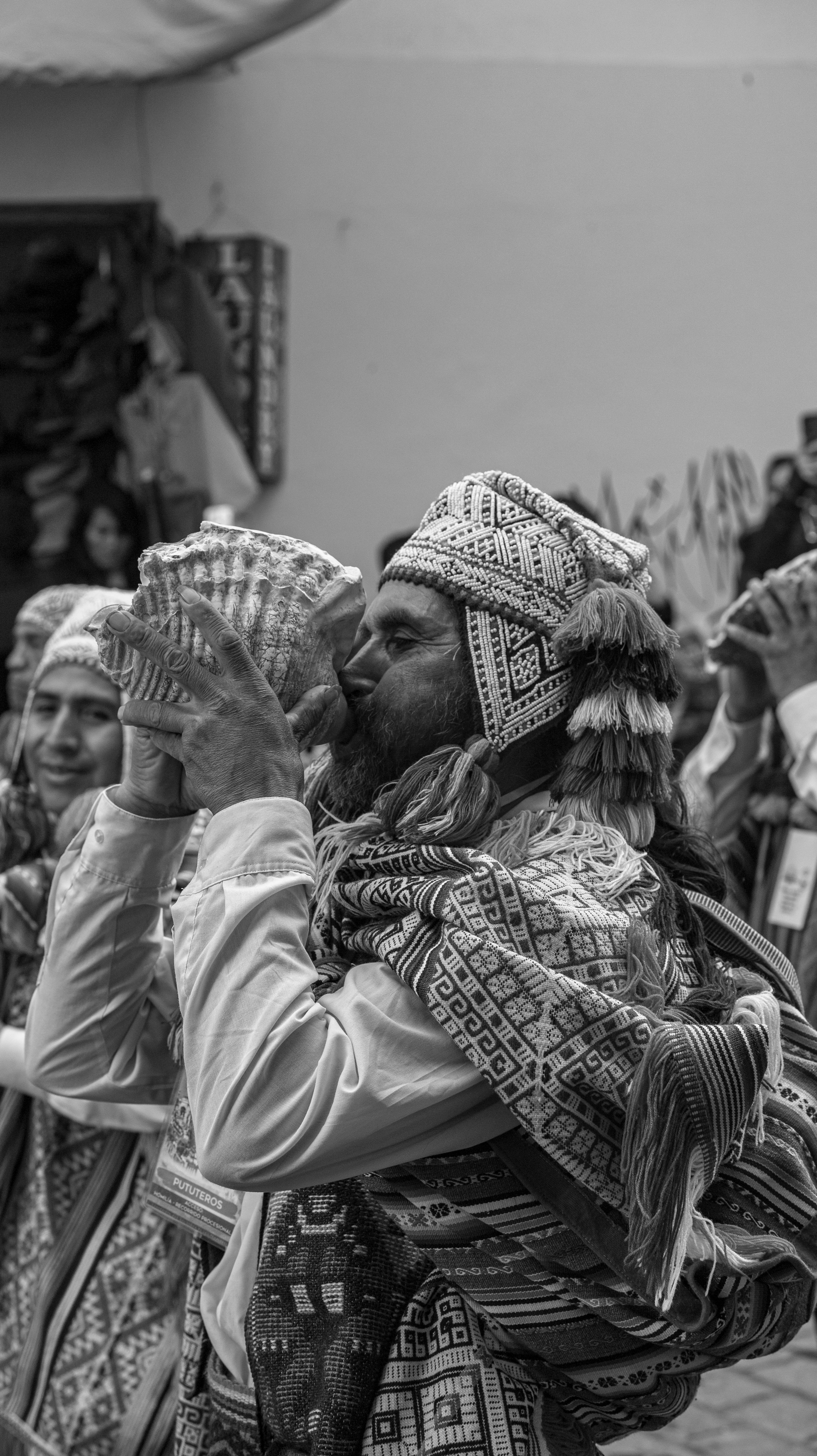 Black and white image of men in traditional clothing playing instruments at a festival.