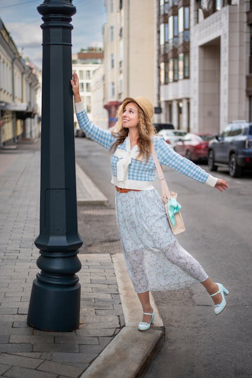 A woman leaning against a street light pole