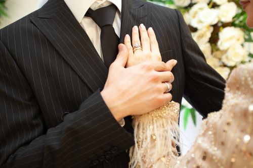 Free Close-up of a couple holding hands, focusing on elegant attire and wedding rings. Stock Photo