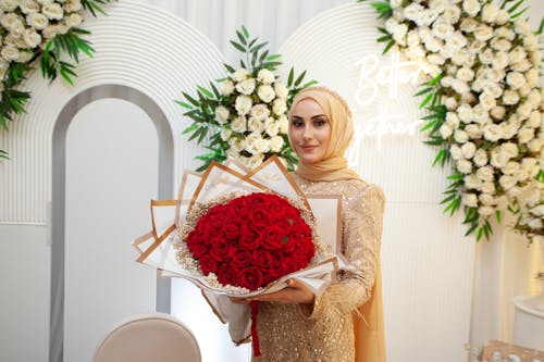 A woman in a hijab holding a bouquet of red roses