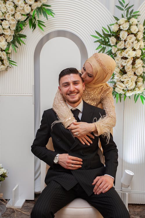 A man and woman hugging each other in front of a floral arrangement