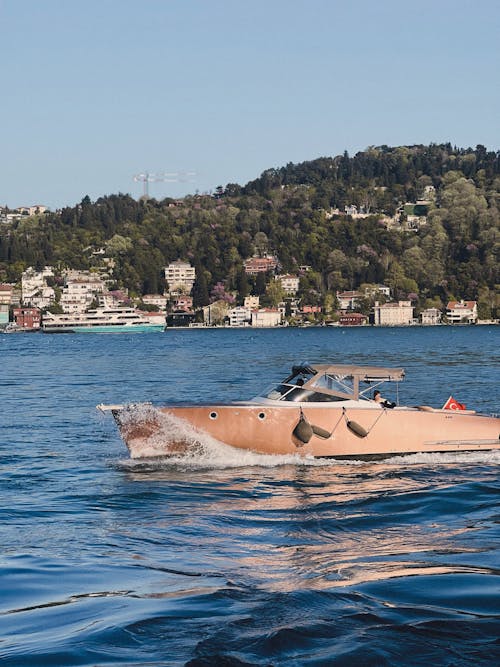A boat is traveling on the water with a hill in the background