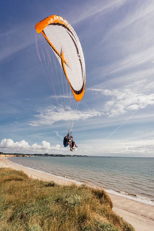 Free Experience the thrill of tandem paragliding over the stunning Pénestin coastline in Brittany, France. Stock Photo