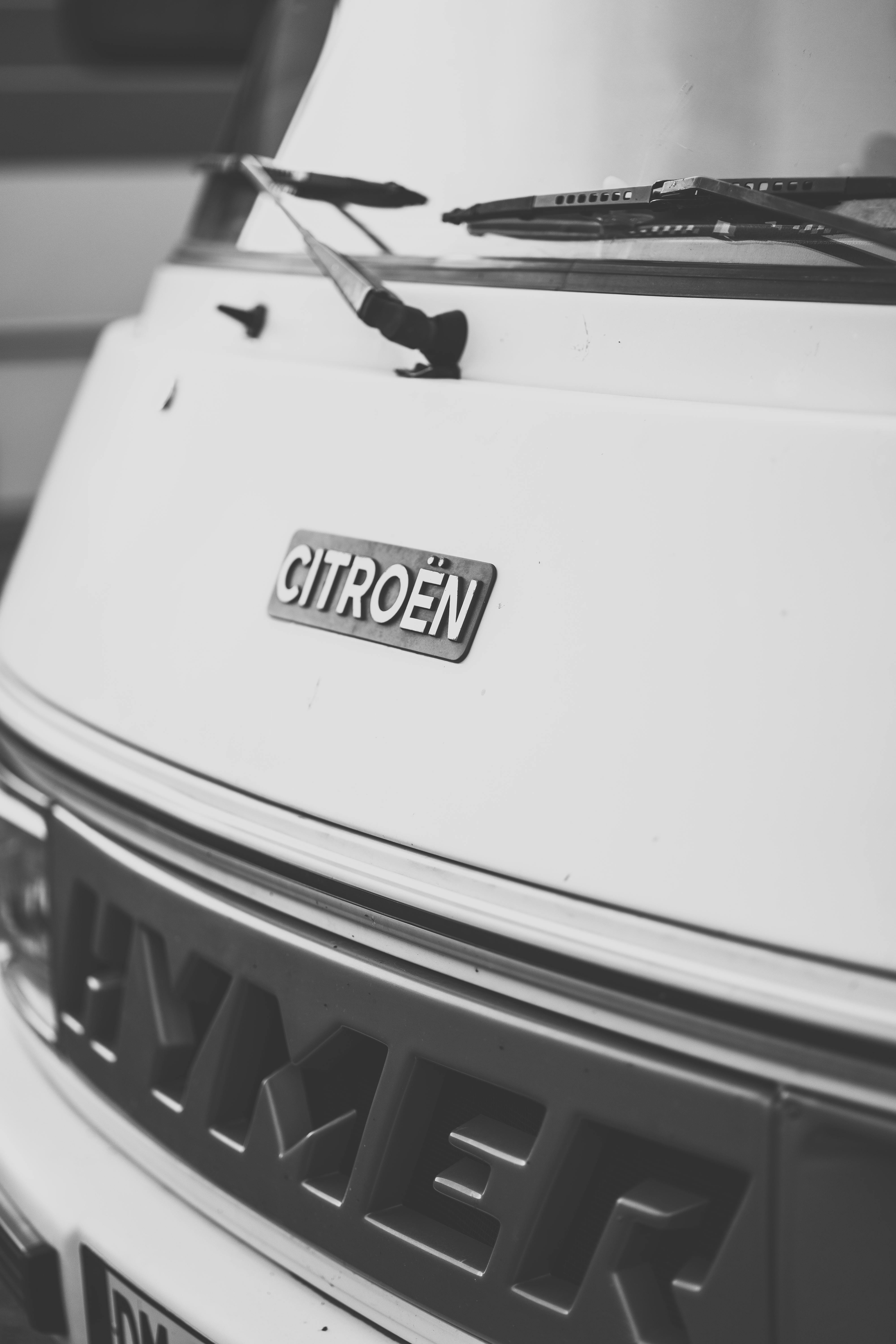 Black and white close-up photo of a Citroën campervan's front emblem, highlighting its vintage style.