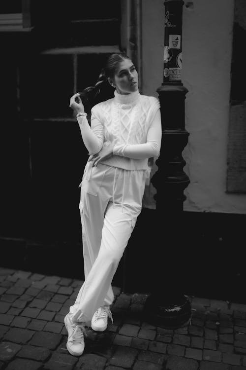 A woman in white pants and a hat is posing for a photo