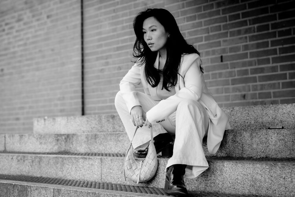 Asian woman in a chic outfit sitting on urban stairs in Köln, Germany.