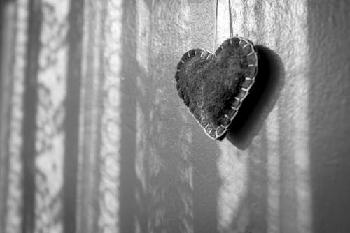 Felt heart hanging on a wall with sunlight and shadows 