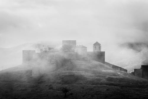 Old castle on a mountain top covered in fog