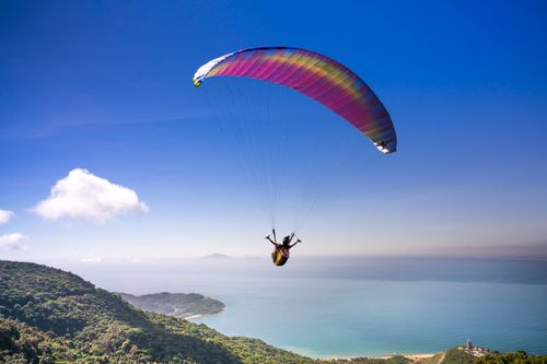 Free Experience the thrill of paragliding over stunning ocean views and lush landscapes. Stock Photo