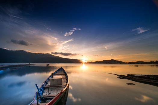 越南富丽湖日落时分，一艘小船静静泊在平静的泻湖上，湖面倒映着温暖的色调