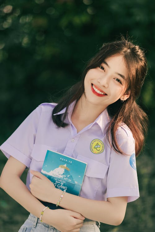 Free A young woman in a purple shirt holding a book Stock Photo