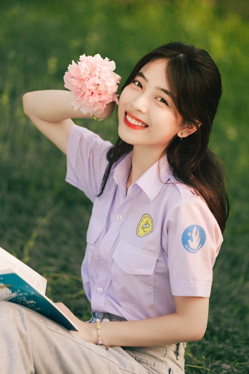 Free Brunette Woman in Shirt and Beige Pants Posing with Pink Flower in Hand Stock Photo