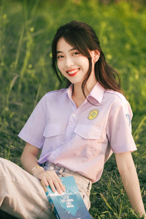 Free Smiling Brunette Sitting on Grass with Book Stock Photo