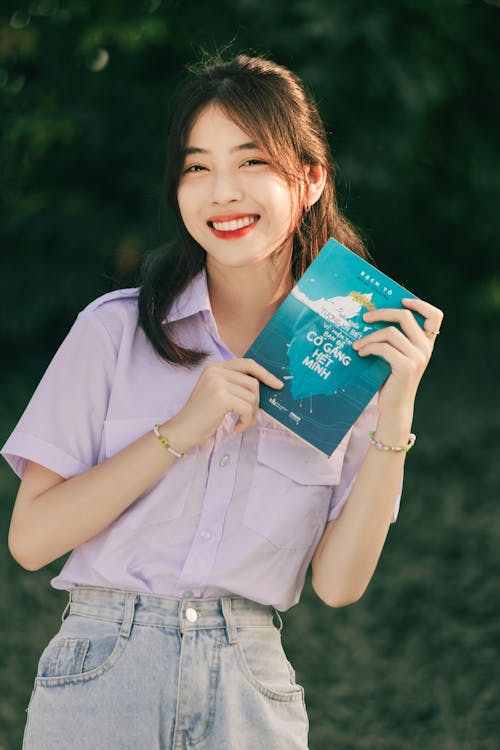 Free A woman in a shirt and jeans holding a book Stock Photo