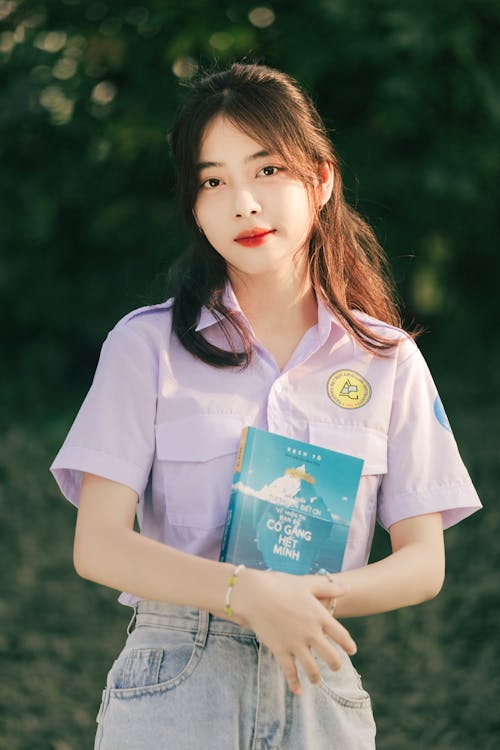 A young woman in a purple shirt holding a book