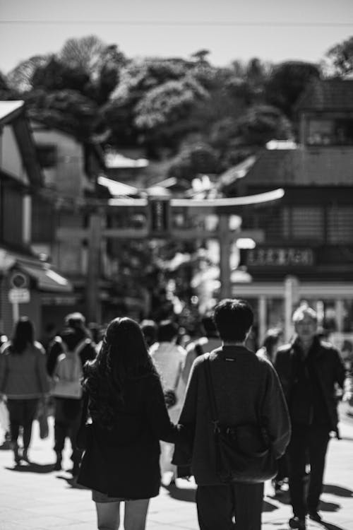 A black and white photo of two people walking down a street