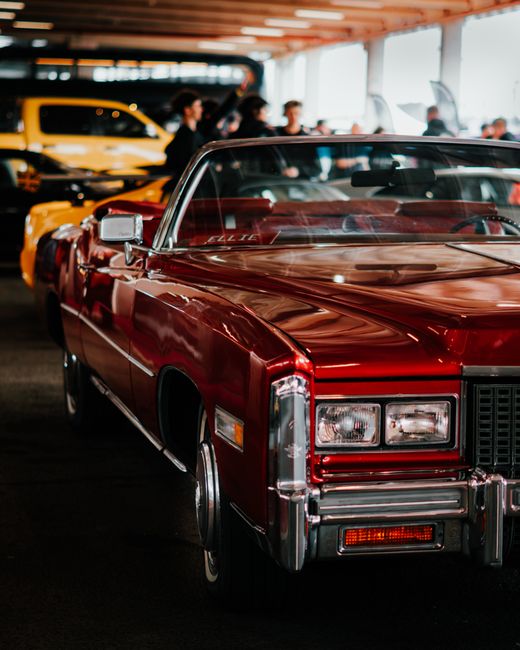 A gleaming red Cadillac Eldorado showcased at an indoor car event, highlighting vintage automotive elegance.