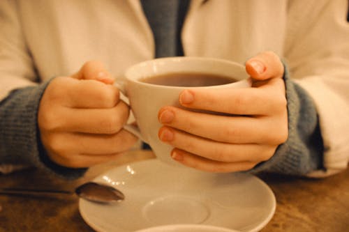 Free A person holding a cup of coffee with a spoon Stock Photo