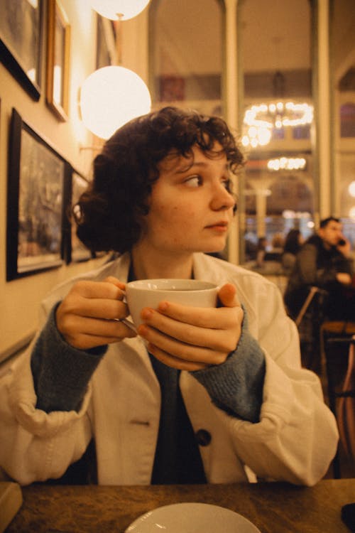 Free A woman holding a cup of coffee in a cafe Stock Photo