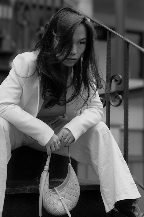 Free A woman in white pants and a purse sits on the steps Stock Photo