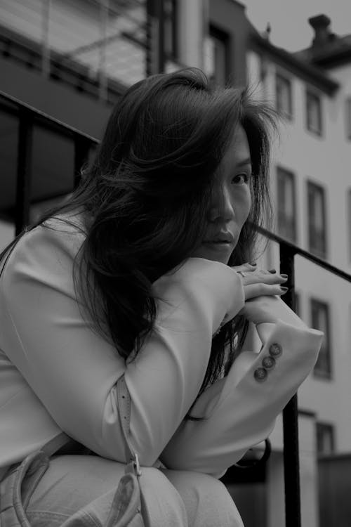 A woman sitting on a railing in black and white