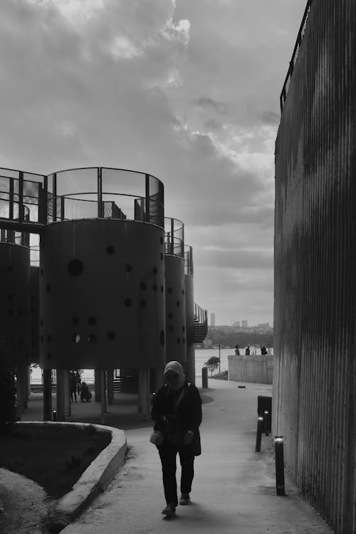 A Person Walking between Modern Constructions in a Park 