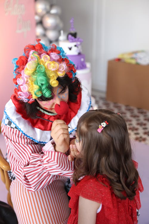 Free A woman with a clown makeup on her face and a little girl Stock Photo