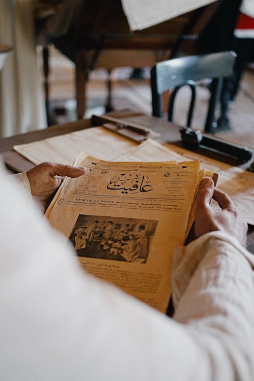 A person reading a newspaper at a table