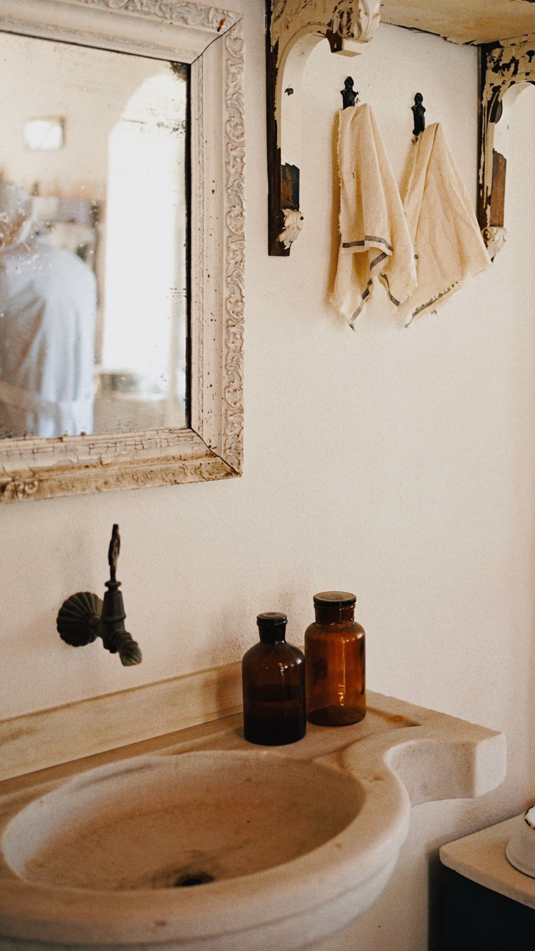 Vintage bathroom sink and framed mirror with a small group of antique-style bottles