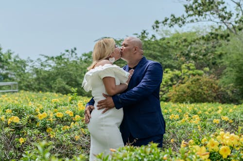 A bride and groom kiss in a field of yellow flowers