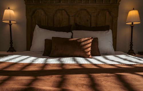 Free A bed with a brown and white comforter and pillows Stock Photo