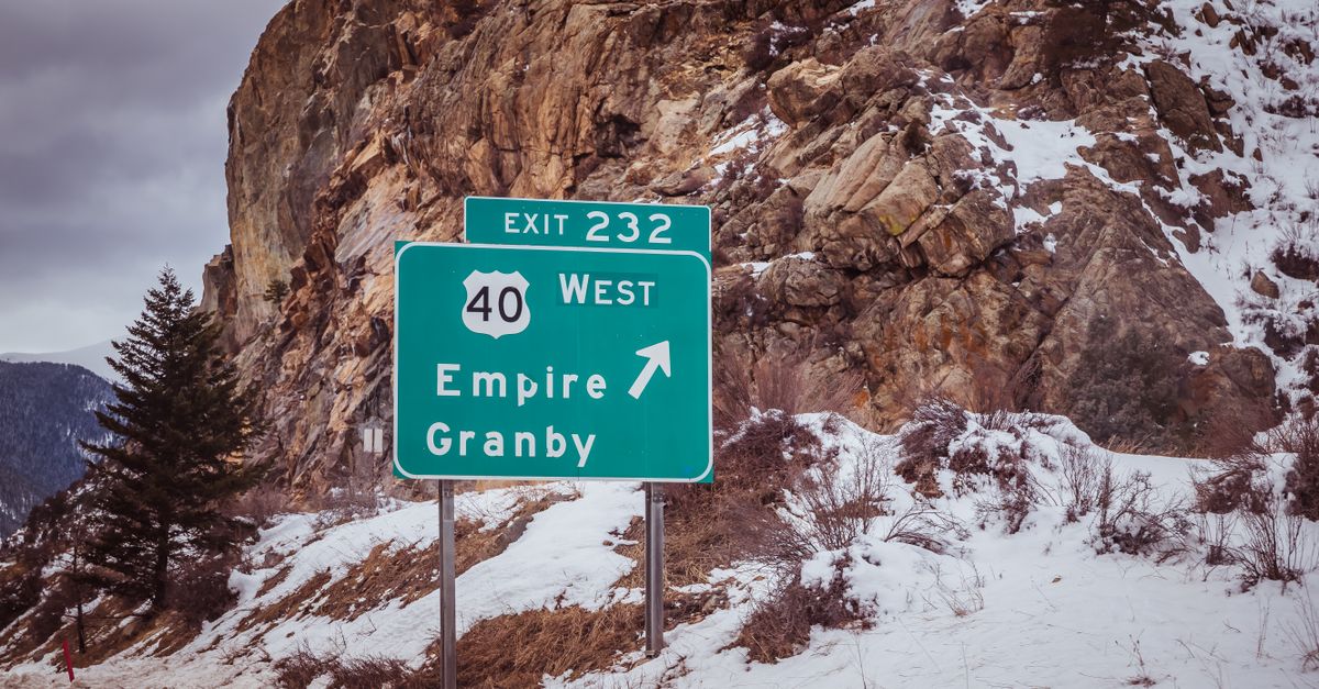 Snowy scene featuring Exit 232 road sign pointing towards Empire and Granby.