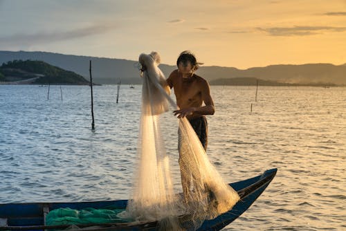 Man Lifting Fish Net On Boat