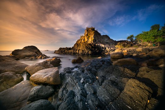 Dramatic rocky seashore landscape with striking twilight sky and colorful tones.