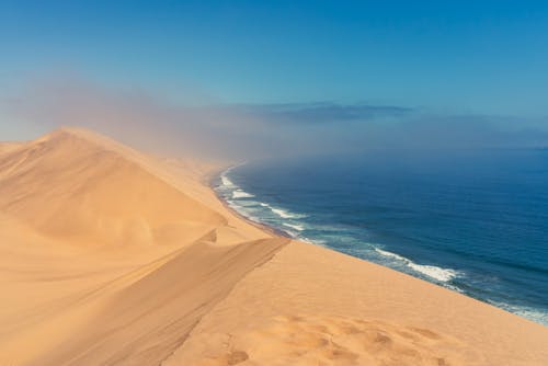 A sand dune with a blue ocean in the background