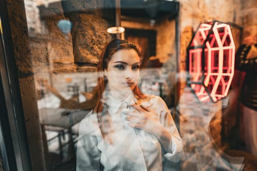 Free A woman looking out of a window at a neon sign Stock Photo