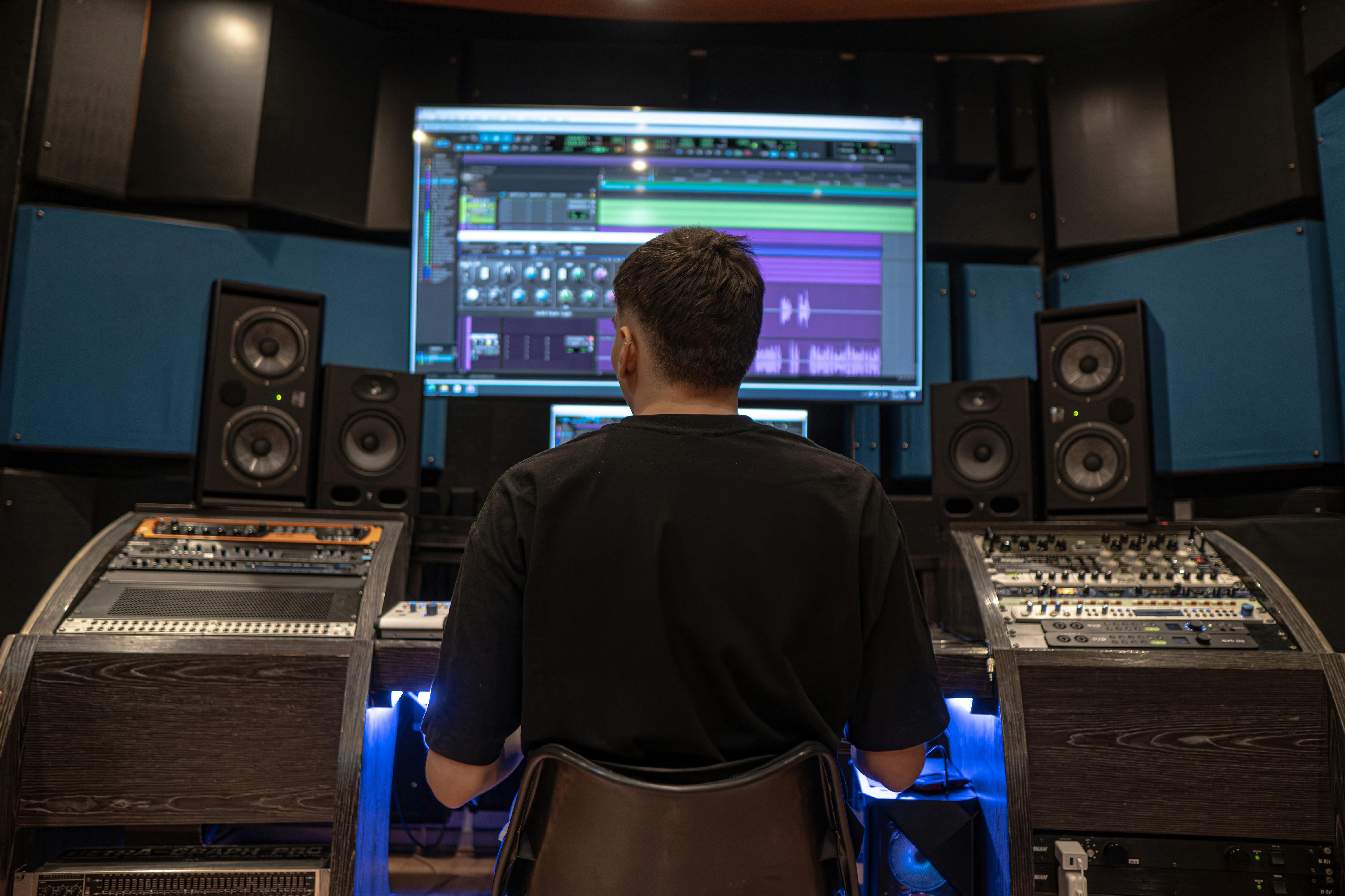 A man focuses on audio editing in a professional recording studio in Medellín.