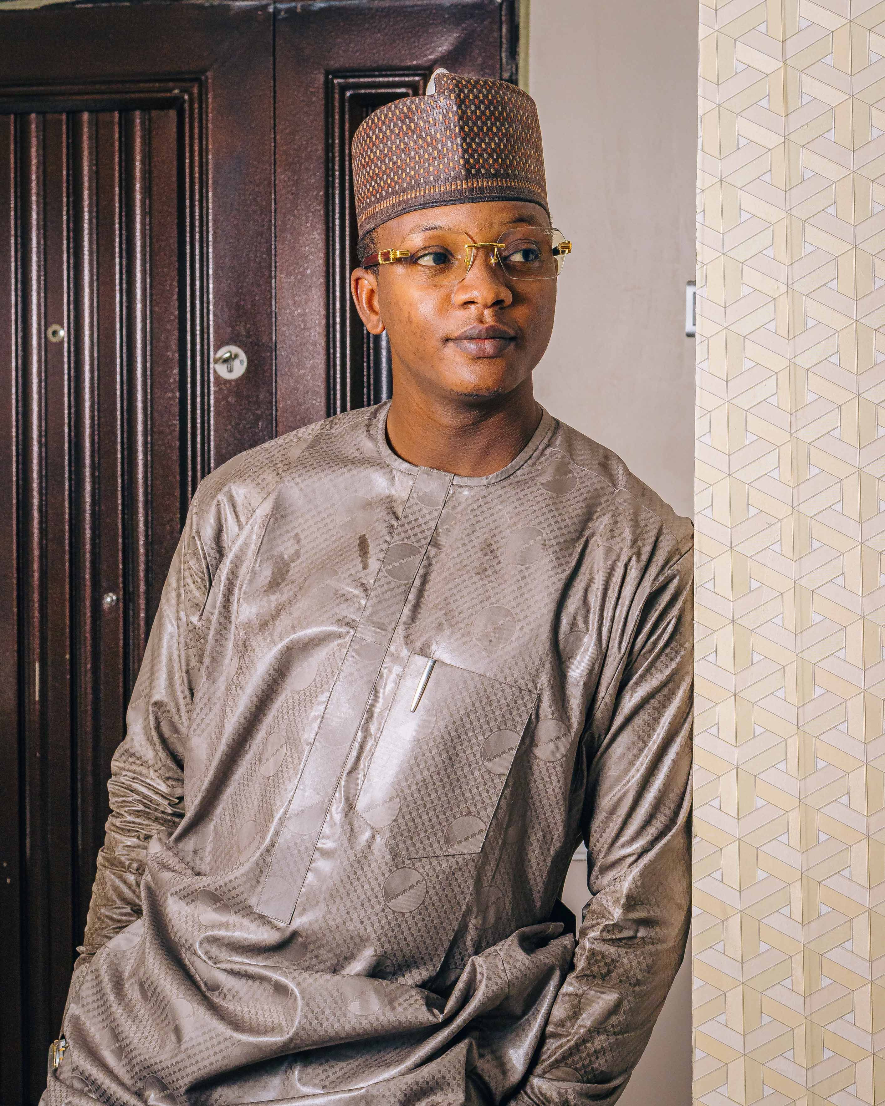 Portrait of a fashionable man wearing a kufi and kurta indoors, showcasing traditional attire and style.