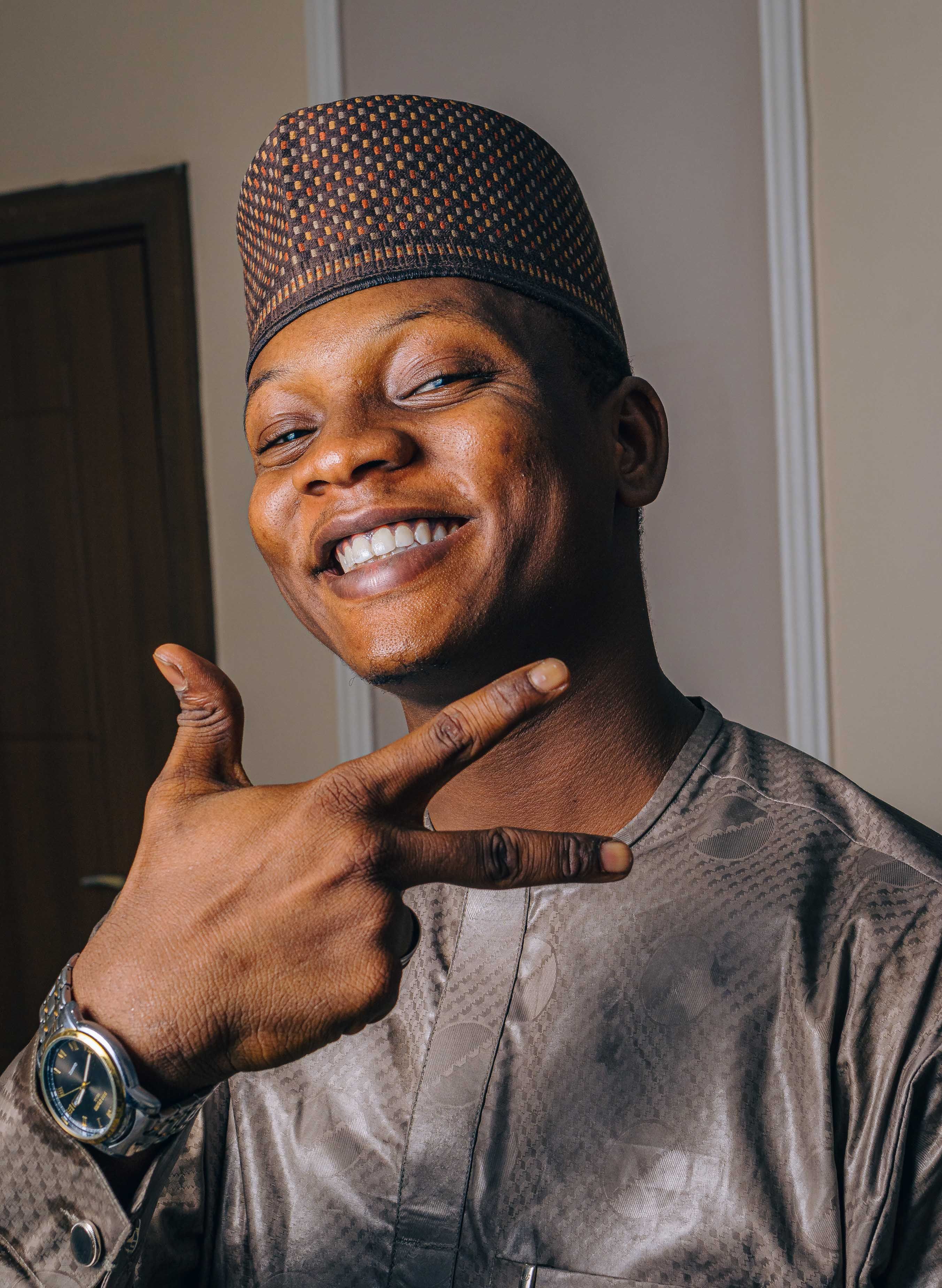 A cheerful man in traditional attire gesturing with confidence indoors.