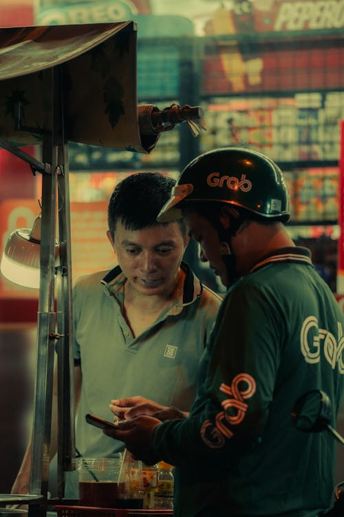 Two men standing next to each other looking at a cell phone