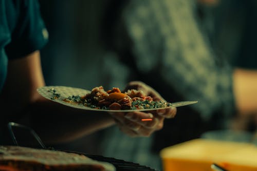 Free A person holding a plate of food on a table Stock Photo