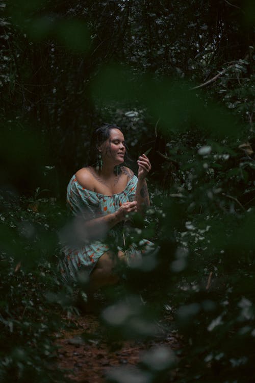 A woman in a dress sitting in the woods