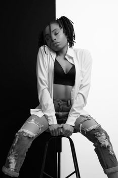 Chic black and white portrait of a young woman in distressed jeans and crop top.