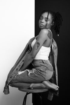 Chic portrait of a woman in denim and white top, posing gracefully in a studio setting.