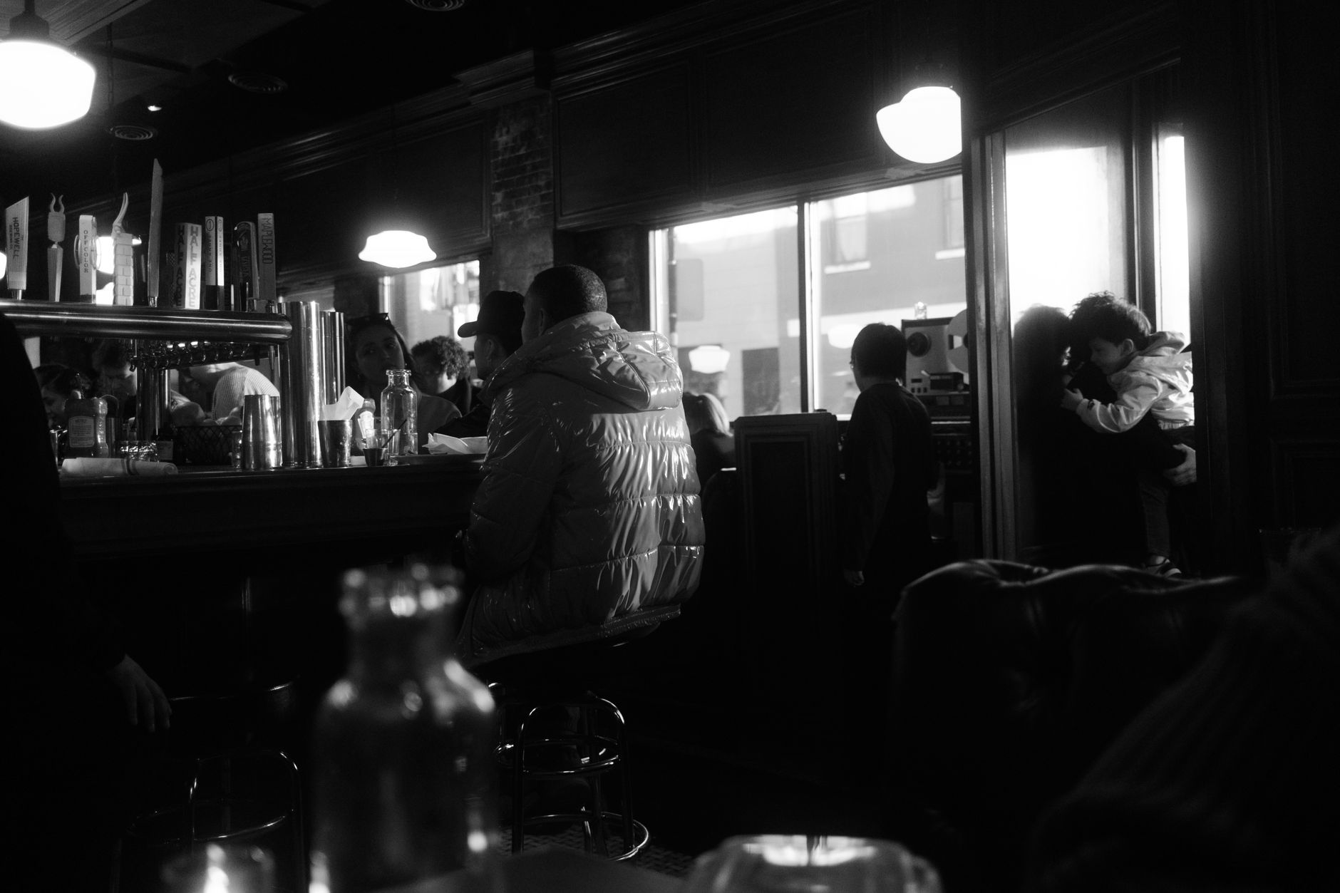 Moody black and white photo of a busy Chicago café bar with people inside.