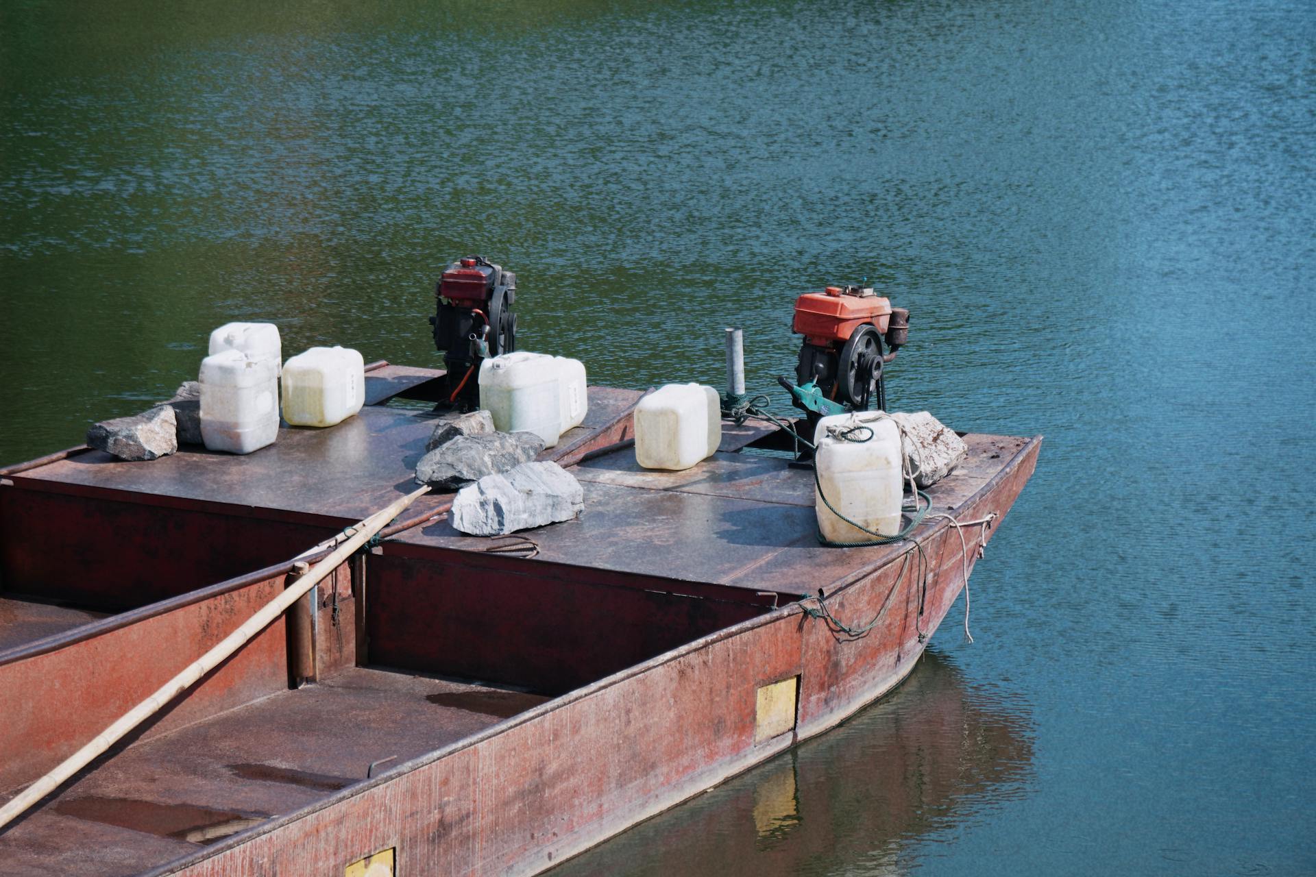 A rusty barge with engines and containers floats on a calm river in Jiujiang, Jiangxi, China.