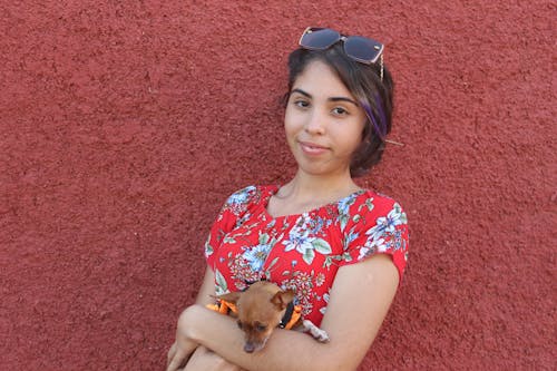 Free A woman in a red shirt holding a small dog Stock Photo